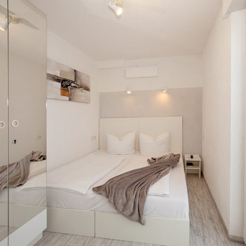 Doppelzimmer mit Spiegelschrank und Fleecedecke auf dem Bett